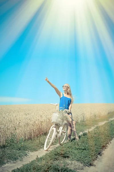 Beautiful blond girl with cycle on the wheat field outdoors background — Stock Photo, Image