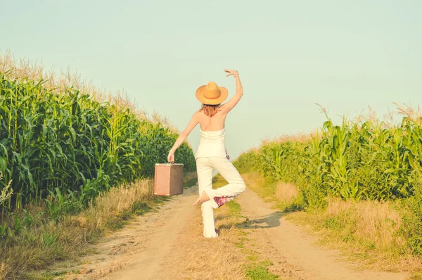 Woman wearing hat standing in ballet pose on country road — Stockfoto
