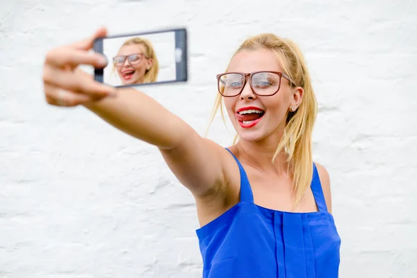 Blond girl in hipster glasses making selfie with loll out — Stock Photo, Image