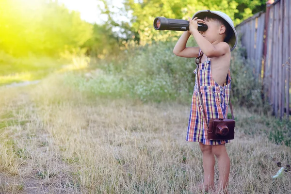 小男孩看着望远镜附近农村的木栅栏 — 图库照片