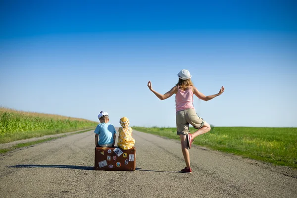 Young woman meditating near two children on summer country road — Stock Photo, Image