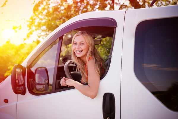 Joven chica rubia riendo conduciendo coche blanco en el fondo de la puesta del sol — Foto de Stock