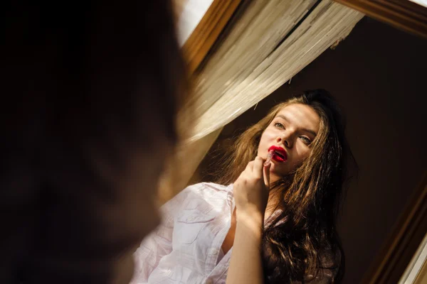 Jovem mulher na camisa aplicando batom vermelho na imagem espelhamento — Fotografia de Stock