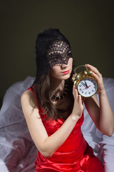 Portrait of beautiful woman in black lace mask holding alarm clock in midnight — Stock Photo, Image