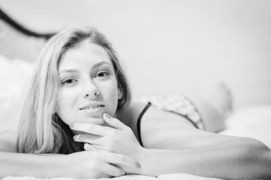 Beautiful young blonde lady having fun relaxing lying in lingerie on bed and happy looking at camera