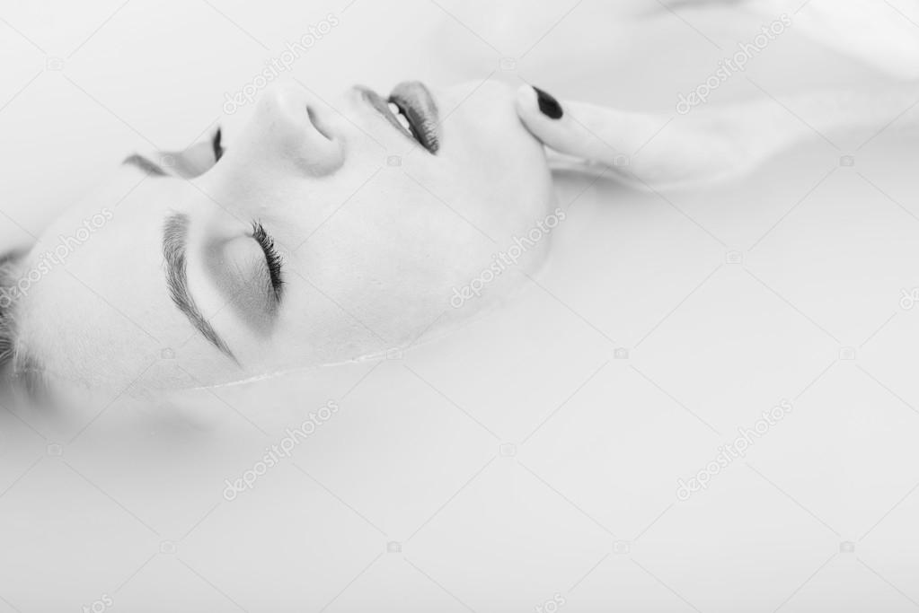 Black and white photography portrait of sexy elegant female with silk skin having fun happy relaxing lying in milk water on copy space background