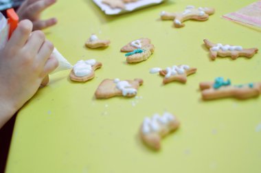 Closeup image of little hand which is decorating Christmas gingerbread