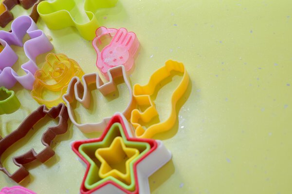 Closeup image of multicolored plastic cookies cutter on green background