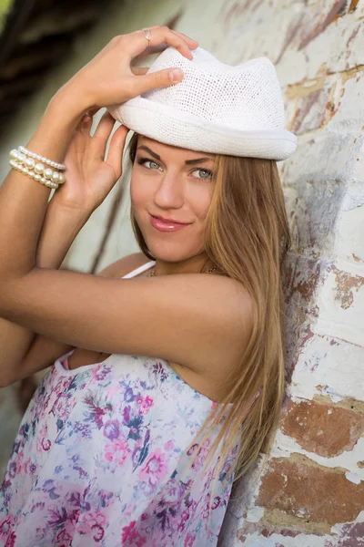 Chica bonita en sombrero fedora blanco al lado de la pared de ladrillo viejo — Foto de Stock