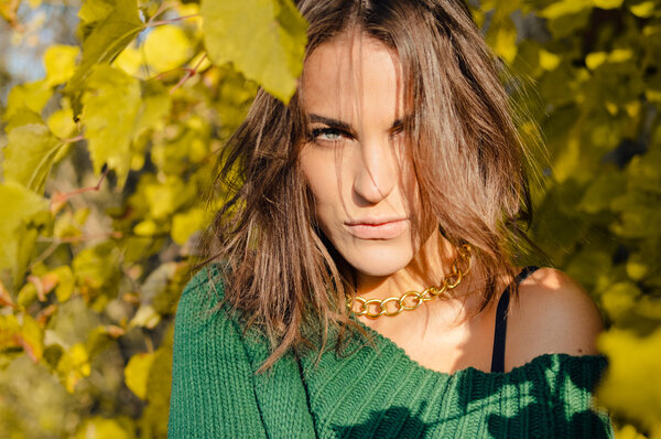 Красивая прячущаяся девушка с запутанными волосами в зеленом свитере в сельской местности
