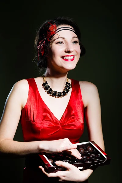 Молодая красивая удивительная женщина в стиле 20-х годов красный костюм с шоколадными конфетами — стоковое фото