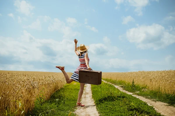 Young happy girl wearing striped dress dancing on country road. — Stockfoto