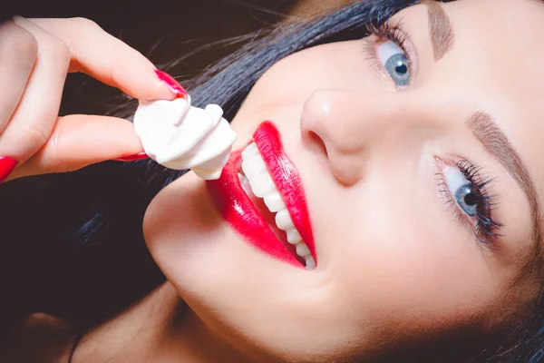 สาวสวยมีริมฝีปากสีแดงสดใสถือมาร์ชเมลโลว์สีขาว — ภาพถ่ายสต็อก
