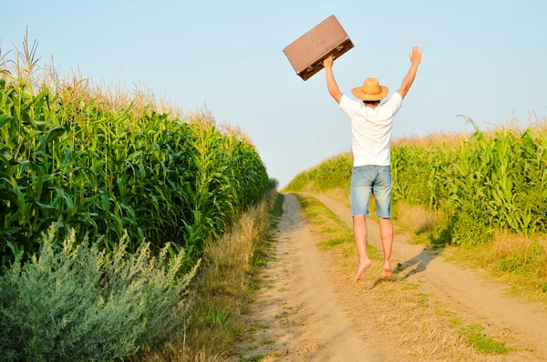 Man with a suitcase on a rural road in summer — Stock fotografie