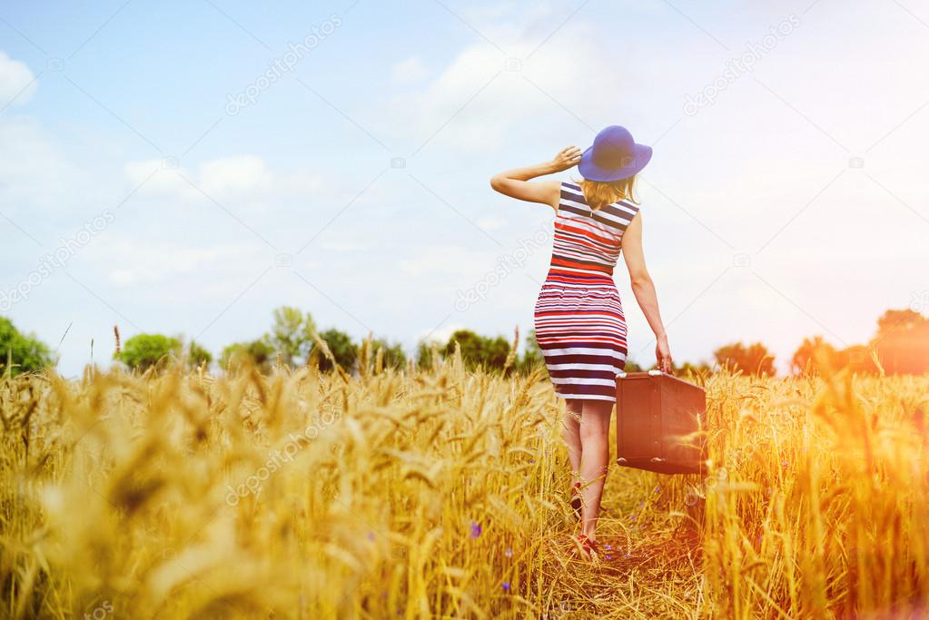 Girl in blue hat walking away in golden sunlight countryside