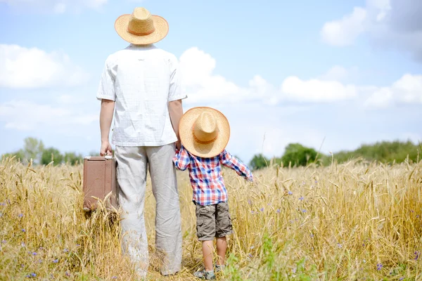 Picture of father and son travelling on summer wheat field and blue sky background