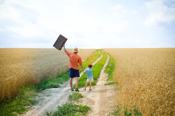 Padre che cammina con suo figlio per strada in un distretto rurale sconfinato — Foto Stock