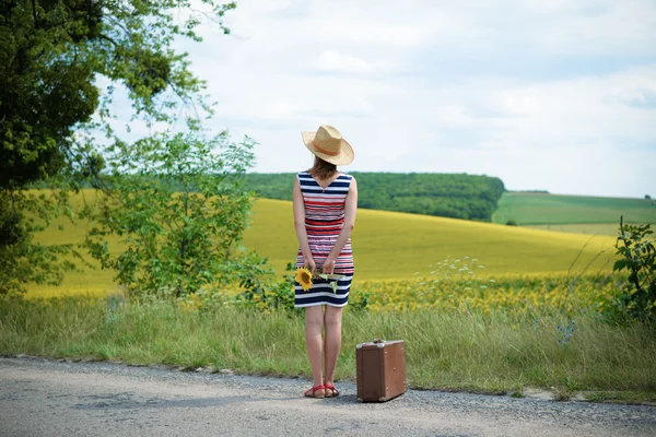 Young lady looking away in the distance and holding a sunflower — Stockfoto