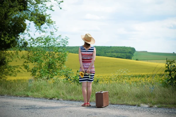 Young lady looking away in the distance and holding a sunflower — 스톡 사진