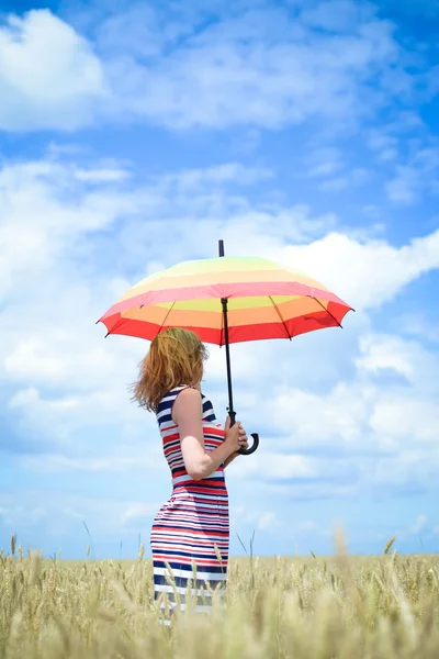 Blond girl holding umbrella and standing in golden wheat field — Stock Photo, Image