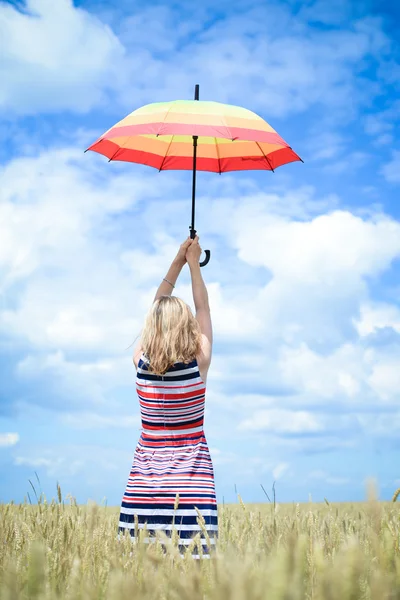 Blond girl rising umbrella and standing in golden wheat field — Stock Photo, Image