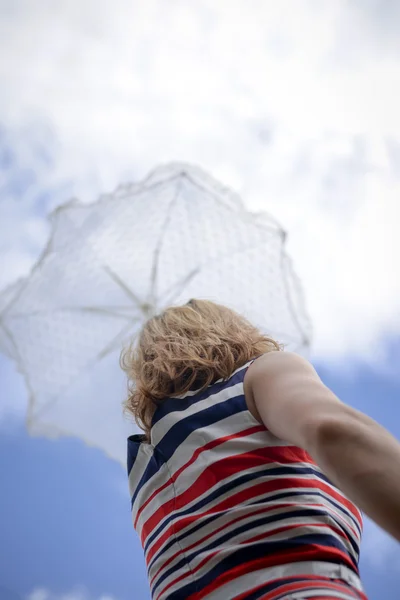 Romantic blond girl looking up at blue sky under white umbrella — ストック写真