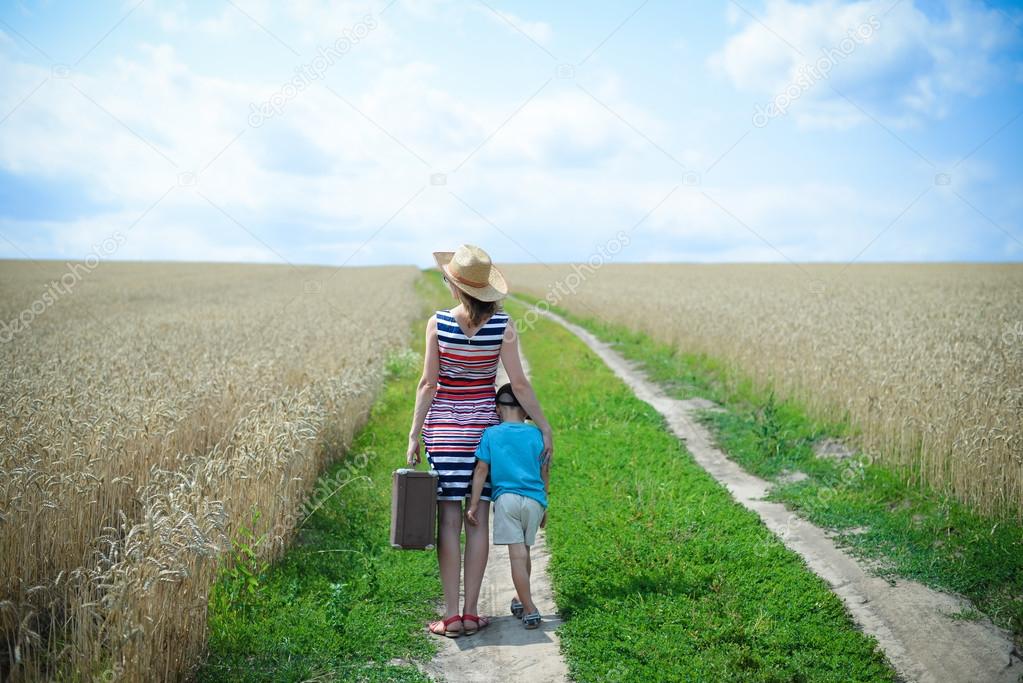 Female and child standing on road between field of wheat