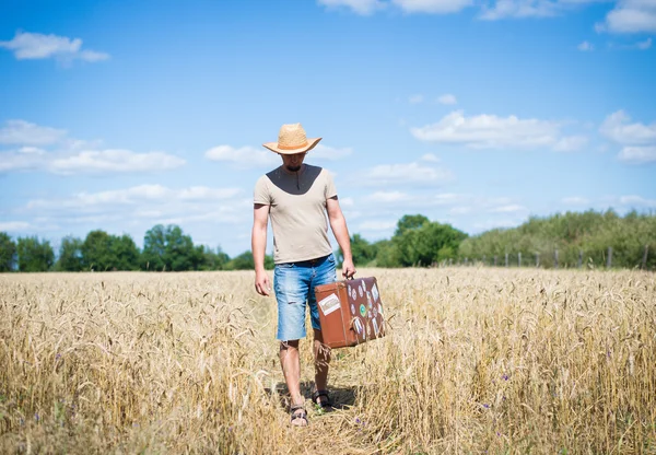 Rural man travelling on the wheat field with a suitcase — Stock Fotó
