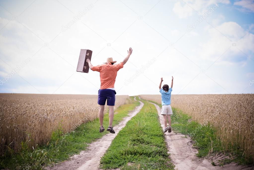 Picture of man and boy jumping on road between field of wheat