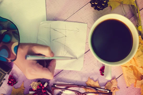Women hand writing graph on napkin with autumn decor beside — 스톡 사진