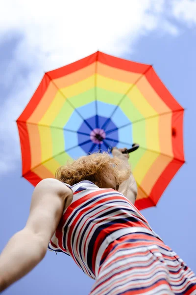 Mulher elegante segurando guarda-chuva arco-íris sobre ensolarado céu azul espaço de cópia de fundo — Fotografia de Stock