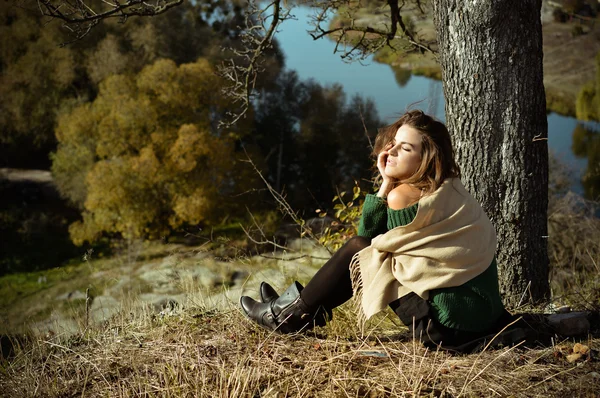 Şal ağacın altında sonbahar nehir sunning içinde büyüleyici kadın