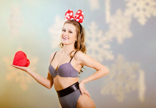 Portret van prachtige spannende vrouw in ondergoed en boog houden hart gevormde doos van de gift — Stockfoto