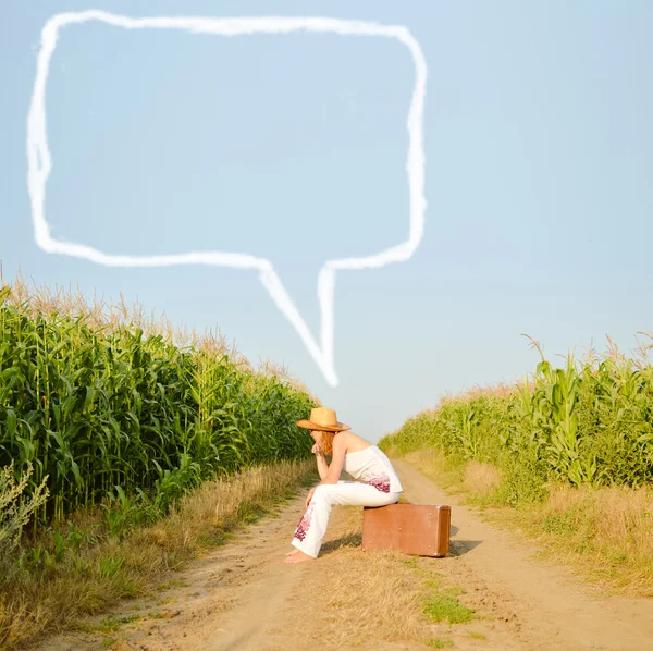 Mooi meisje, zittend op koffer met gedachte zeepbel in platteland — Stockfoto