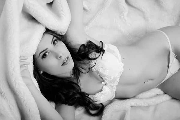 Imagem de bela jovem sensual adorável deitado na cama e olhando sensualmente para a câmera. Fotografia em preto e branco — Fotografia de Stock
