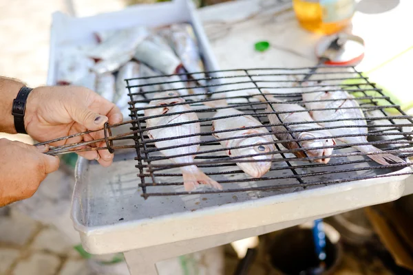 Mâle main fermeture grille métallique avec quatre poissons pour grill — Photo
