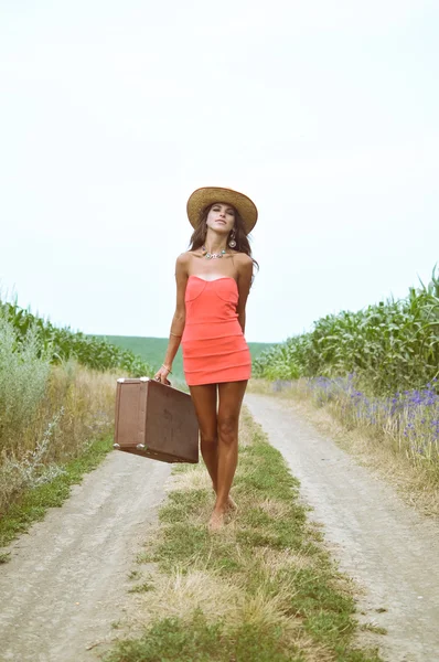 Menina sexy andando com mala velha ao lado do campo de milho de verão — Fotografia de Stock