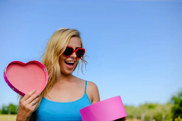 멋진 선글라스 핑크 마음 열기에 흥분된 여자 giftbox 모양 — 스톡 사진