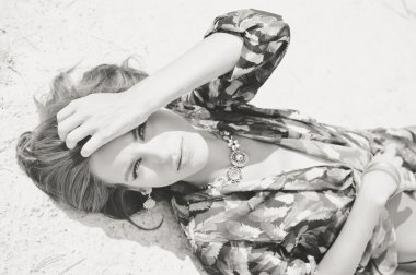 Closeup portrait of beautiful sexy young lady laying on the sand ground on sunshine outdoors background