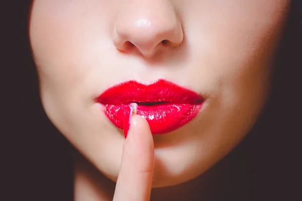Rode lippen van mooie jonge dame shushing op onscherpe achtergrond — Stockfoto