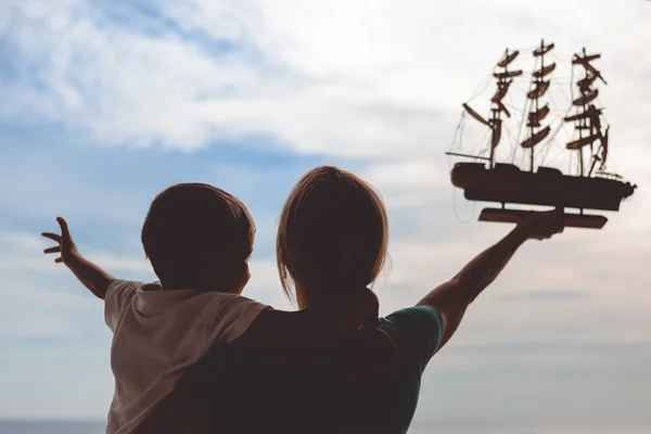 Silhueta de mulher feliz animado e menino segurando modelo de navio — Fotografia de Stock