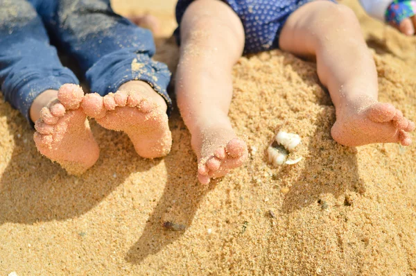 Closeup of two childrens legs barefoot on summer sand seashore — ストック写真