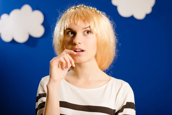 Beautiful young lady in golden wig on paper clouds background — Stock fotografie