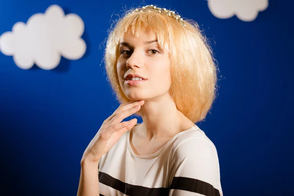 Beautiful young female in wig beside wall with paper clouds — Stock Photo, Image
