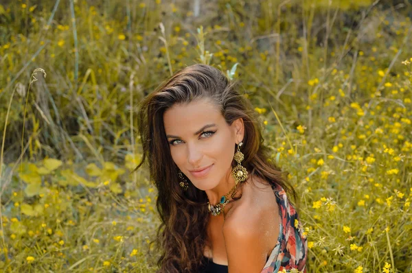 Hermosa joven con collar de lujo sentado en flores silvestres amarillas — Foto de Stock