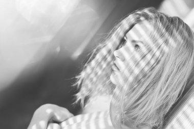 Sensual pretty lady with shadow from window blinds on shoulders having fun looking at sun light flare rays on light copy space background