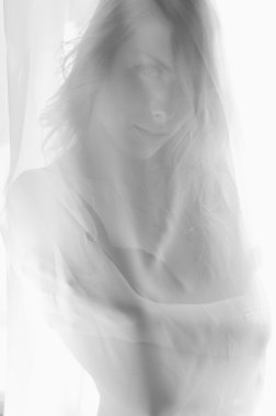 Beautiful young lady having fun hiding in lingerie and happy relaxing looking at camera on window light copy space background