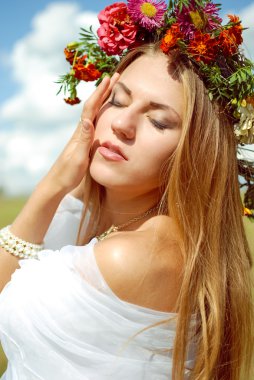 Beautiful young lady in white chiffon shawl and flower wreath