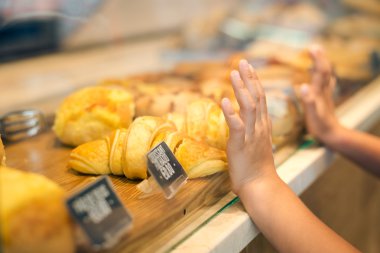 Closeup of childs hands on glass wanting to choose croissant