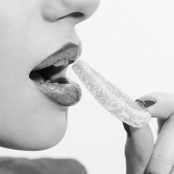 Imagem close-up de bela senhora sensual de luxo com lábios sedutores, dentes brancos excelentes e unhas de manicure mordendo jujuba ou doces . — Fotografia de Stock